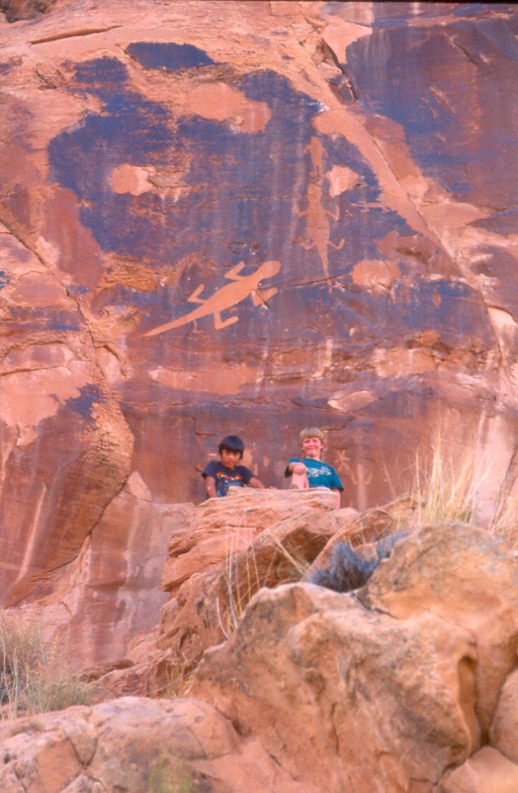 Children sitting in front of a petroglyph