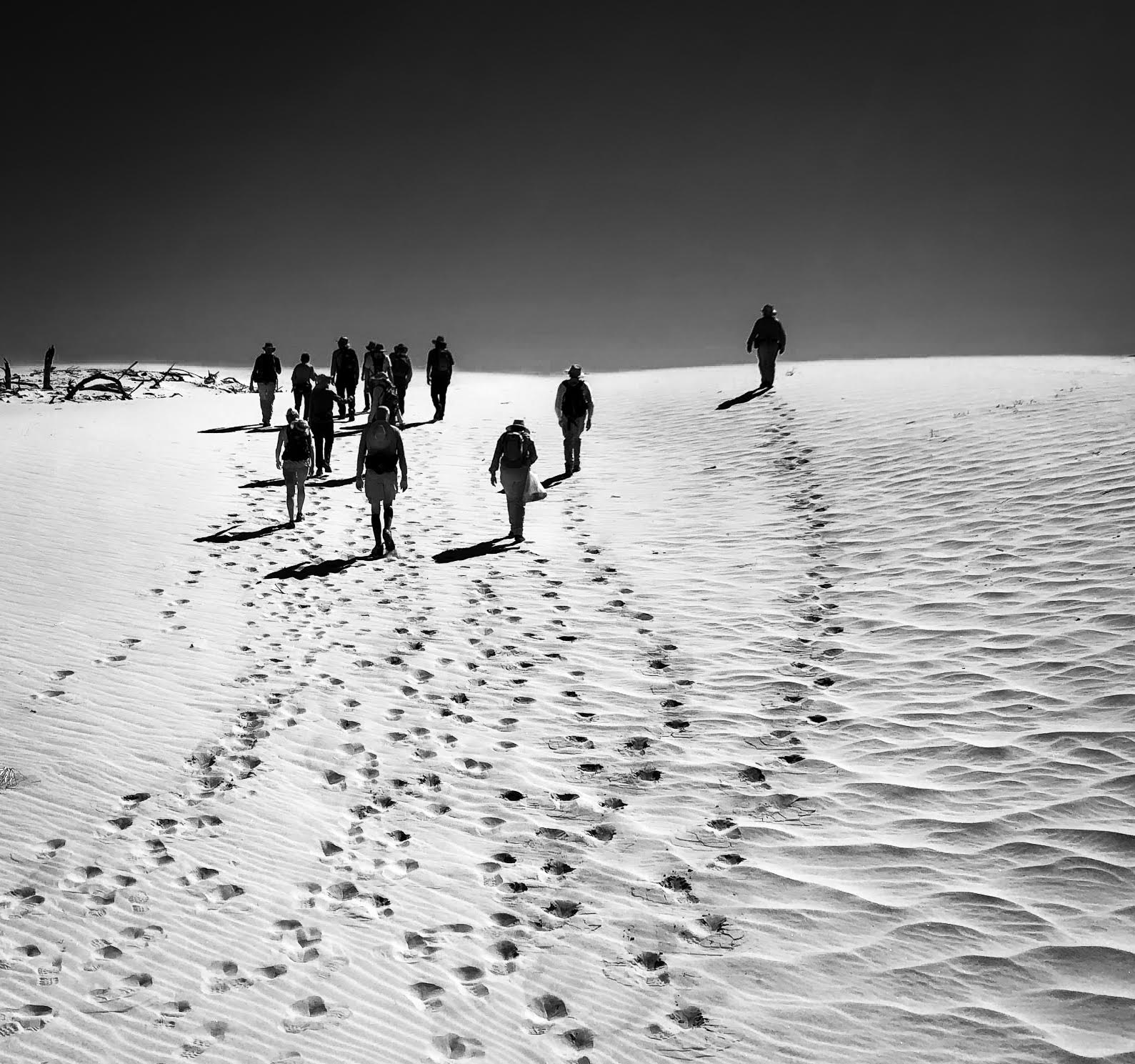 People walking on sand dunes in a black and white photo