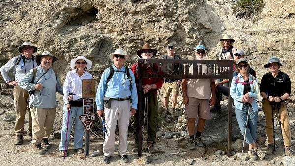 A group of community scientists standing at a trail sign 