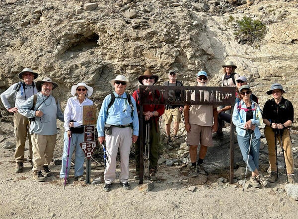 A group of community scientists standing at a trail sign 