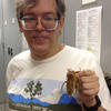 Doug Yanega holding a beetle that's the size of a deck of playing cards